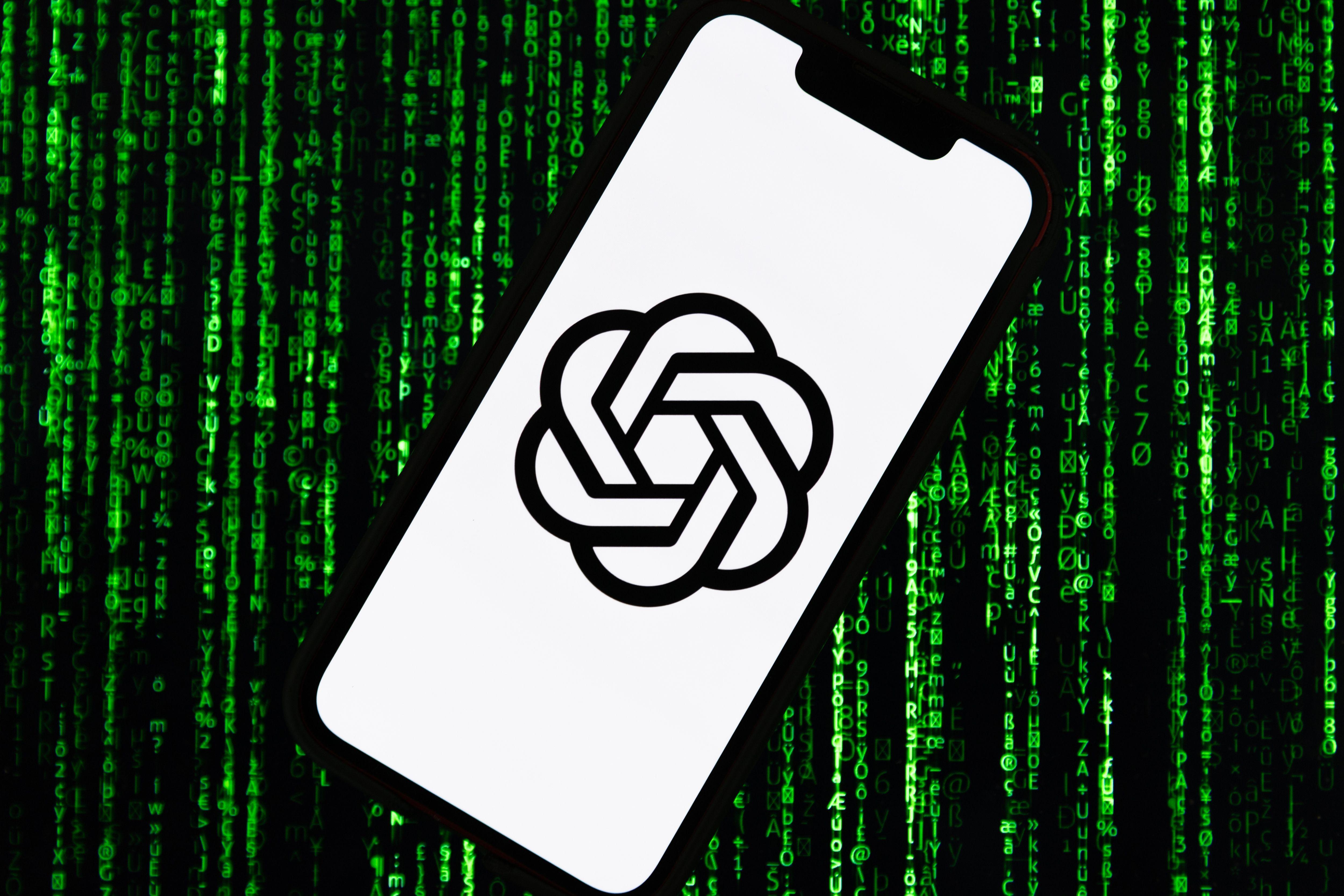 هاتف يحمل شعار تشات جي بي تي على خلفية بيضاء. وخلف الهاتف الأسود خلفية سوداء مليئة بالبيانات ذات اللون الأخضر.