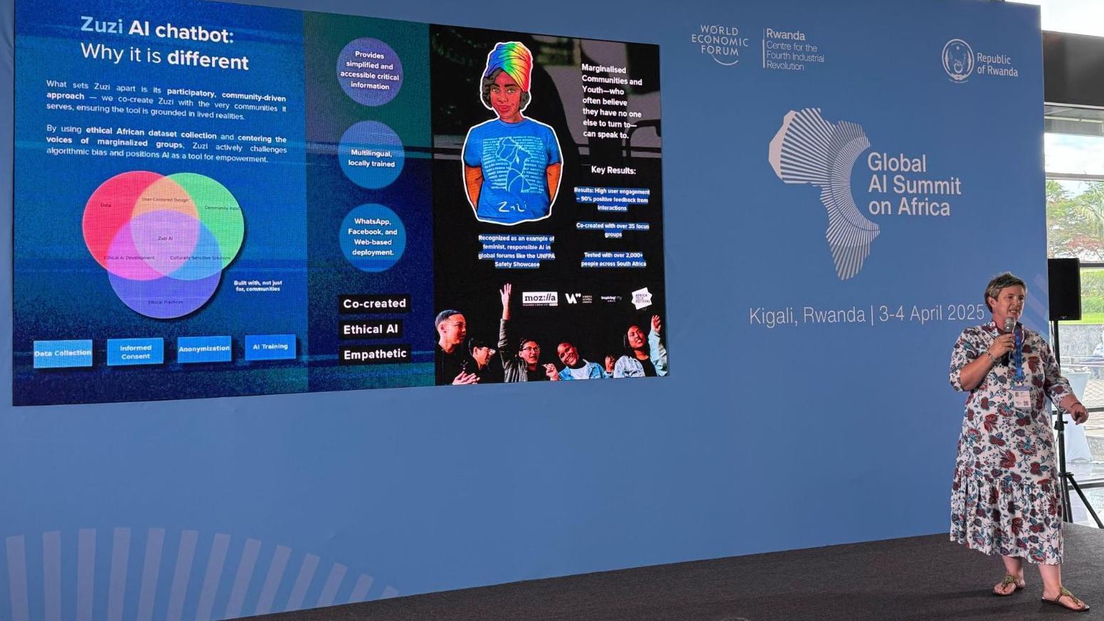 Leonora Tima predstavlja Zuzi na Globalnom samitu veštačke inteligencije u Africi. Slajd iza nje je plave boje i opisuje Zuzi četbota za veštačku inteligenciju, ističući njegov pristup vođen zajednicom, ko-kreaciju sa marginalizovanim zajednicama i korišćenje afričkih skupova podataka. Događaj organizuje Svetski ekonomski forum u Ruandi.