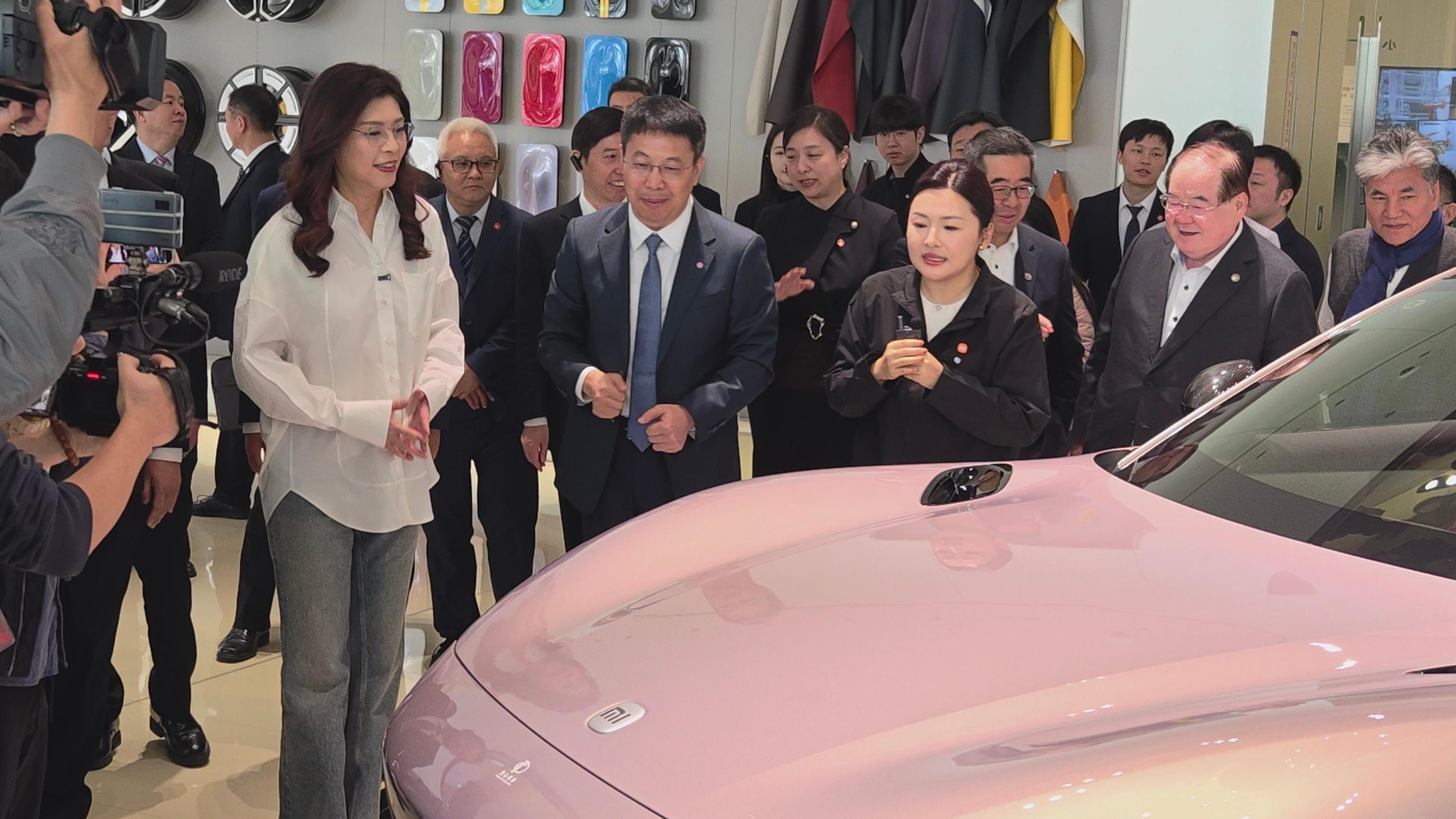 鄭麗文（左一，白色襯衫）在北京小米汽車工廠聽取廠方介紹其汽車（中新社圖片12/4/2026）