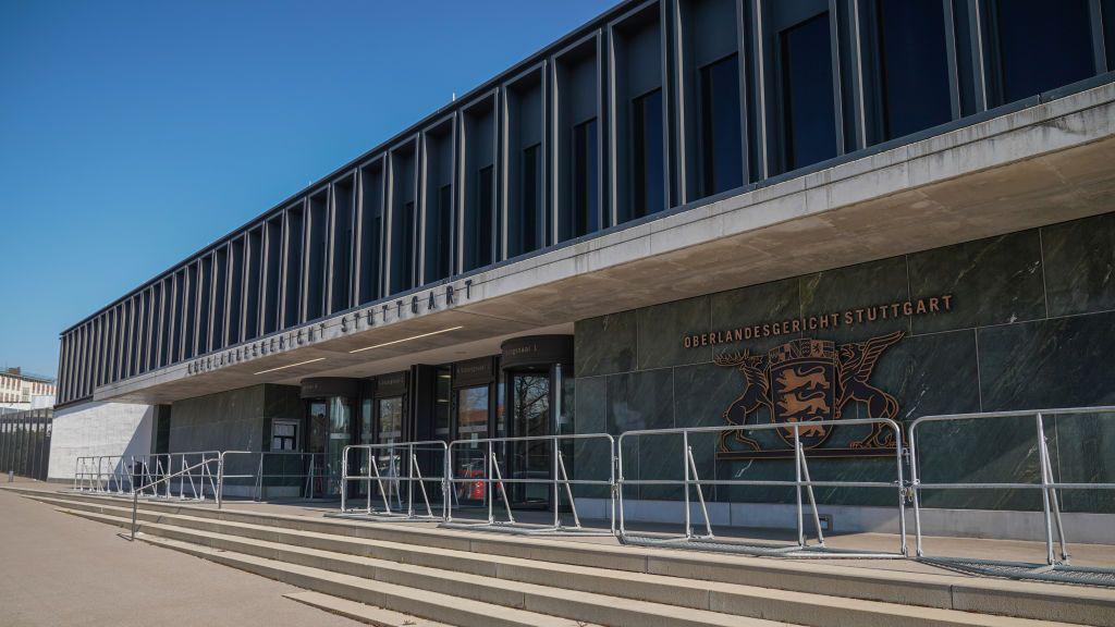 Un edificio con muros de piedra verde y gris, con un emblema dorado en el lateral que reza «Oberlandesgericht Stuttgart».