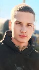 Retrato de Aleksandr Vinshu, um jovem de cabelos bem curtos vestindo uma blusa preta.