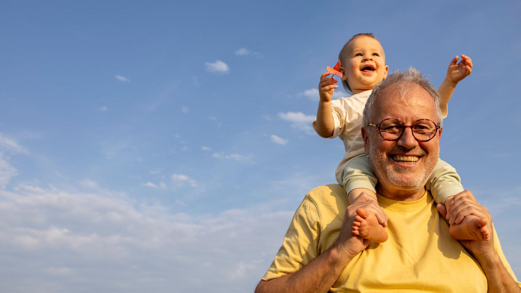 رجل يبتسم ويحمل على كتفه طفلا يبتسم