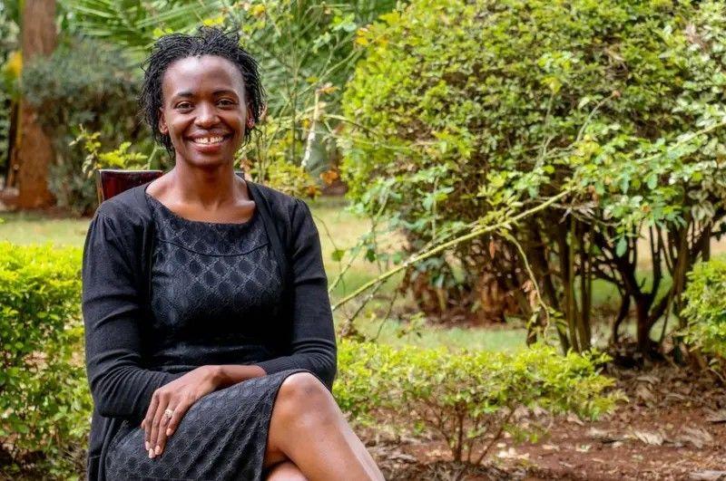 Terry sentada em um banco e sorrindo. No fundo h&aacute; &aacute;rvores