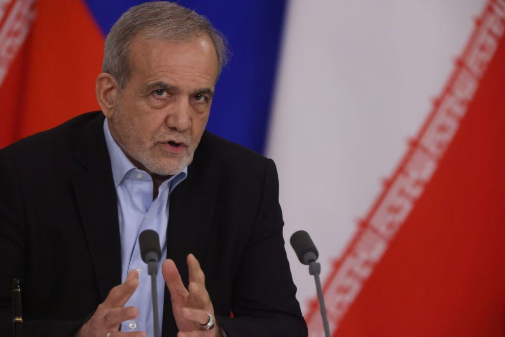 ترامب "ينتظر الوقت المناسب" لرفع العقوبات عن إيران، والرئيس الإيراني يكشف عن محاولة إسرائيلية لاغتياله 1 صورة للرئيس الإيراني، مسعود بزشكيان، وهو يتحدث وأمامه ميكروفون ويظهر في الخلفية علم إيران.