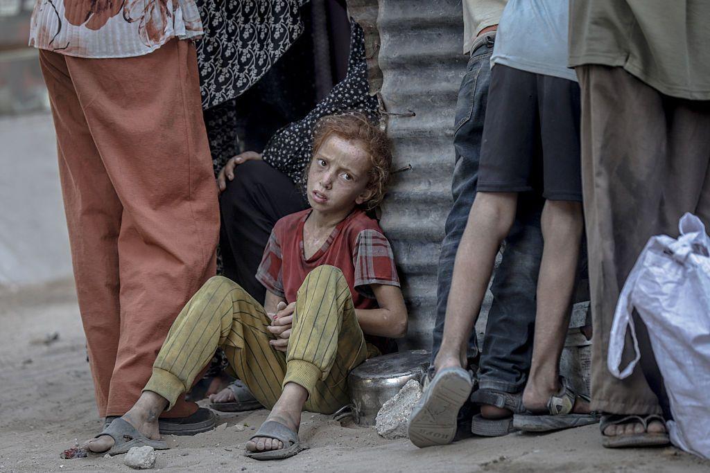 Una niña palestina espera sentada al lado de una olla vacía a recibir alimentación