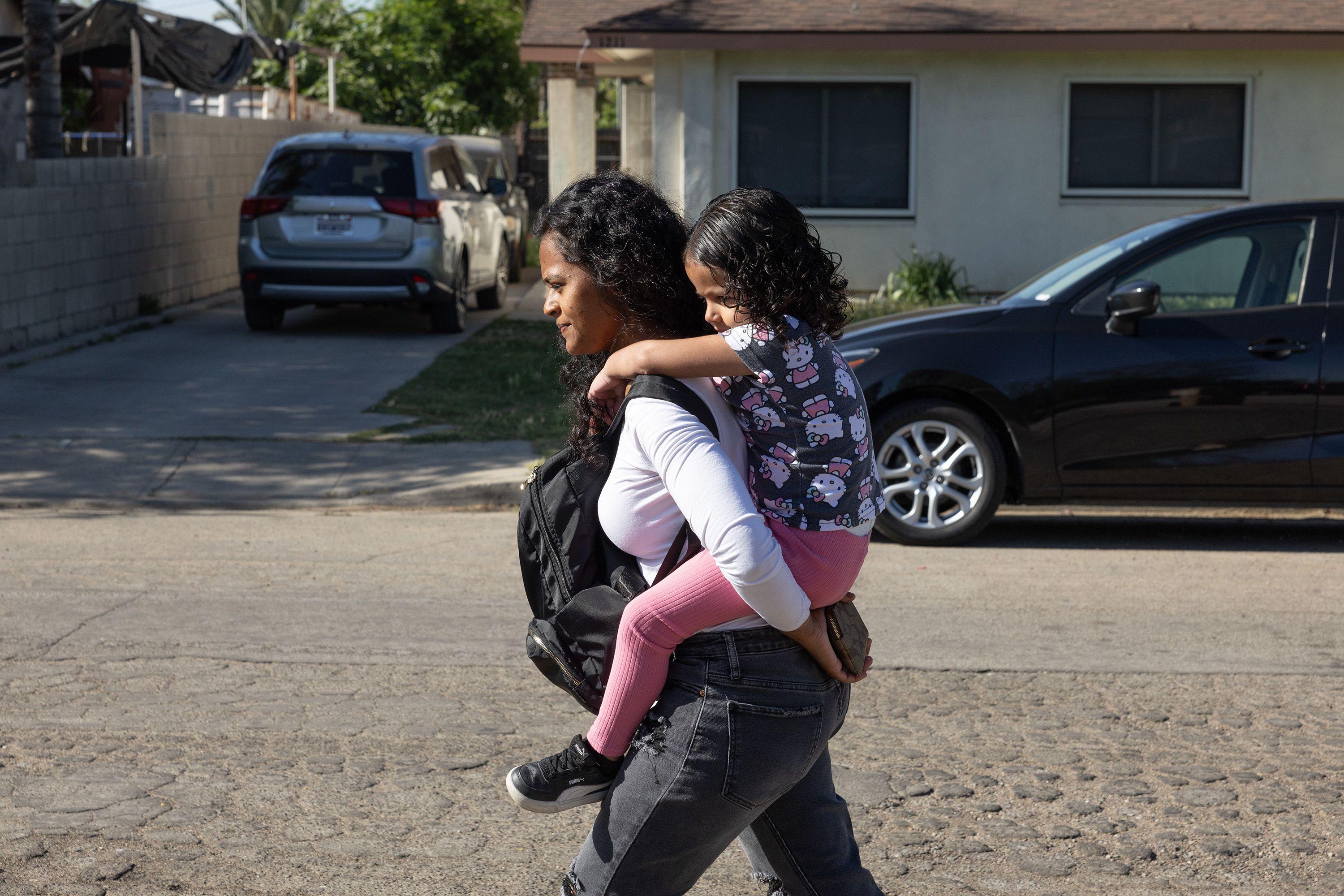 Deysi Vargas carga a su hija Sofía (seudónimo) hasta su escuela en Bakersfield, California, Estados Unidos, el viernes 23 de mayo de 2025. (Myung J. Chun / Los Angeles Times a través de Getty Images).