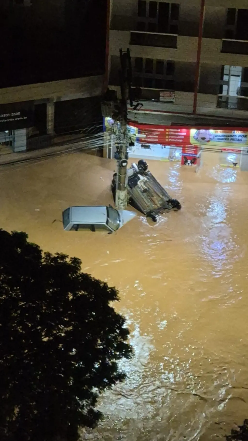 Imagem de dois carros de cabeça para baixo sendo arrastados pela enchente em Uba