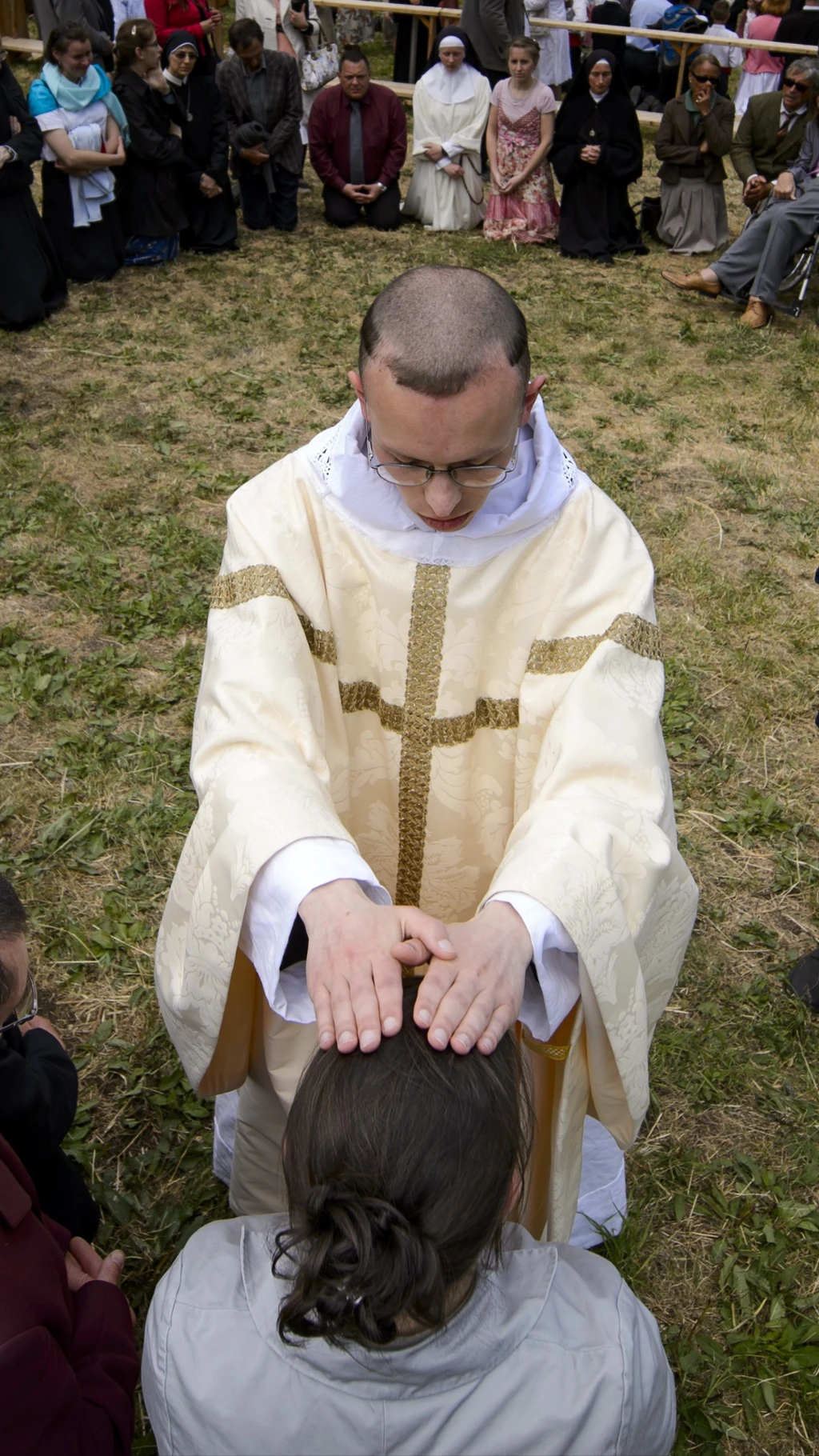 sacerdote impone sus manos sobre una persona arrodillada