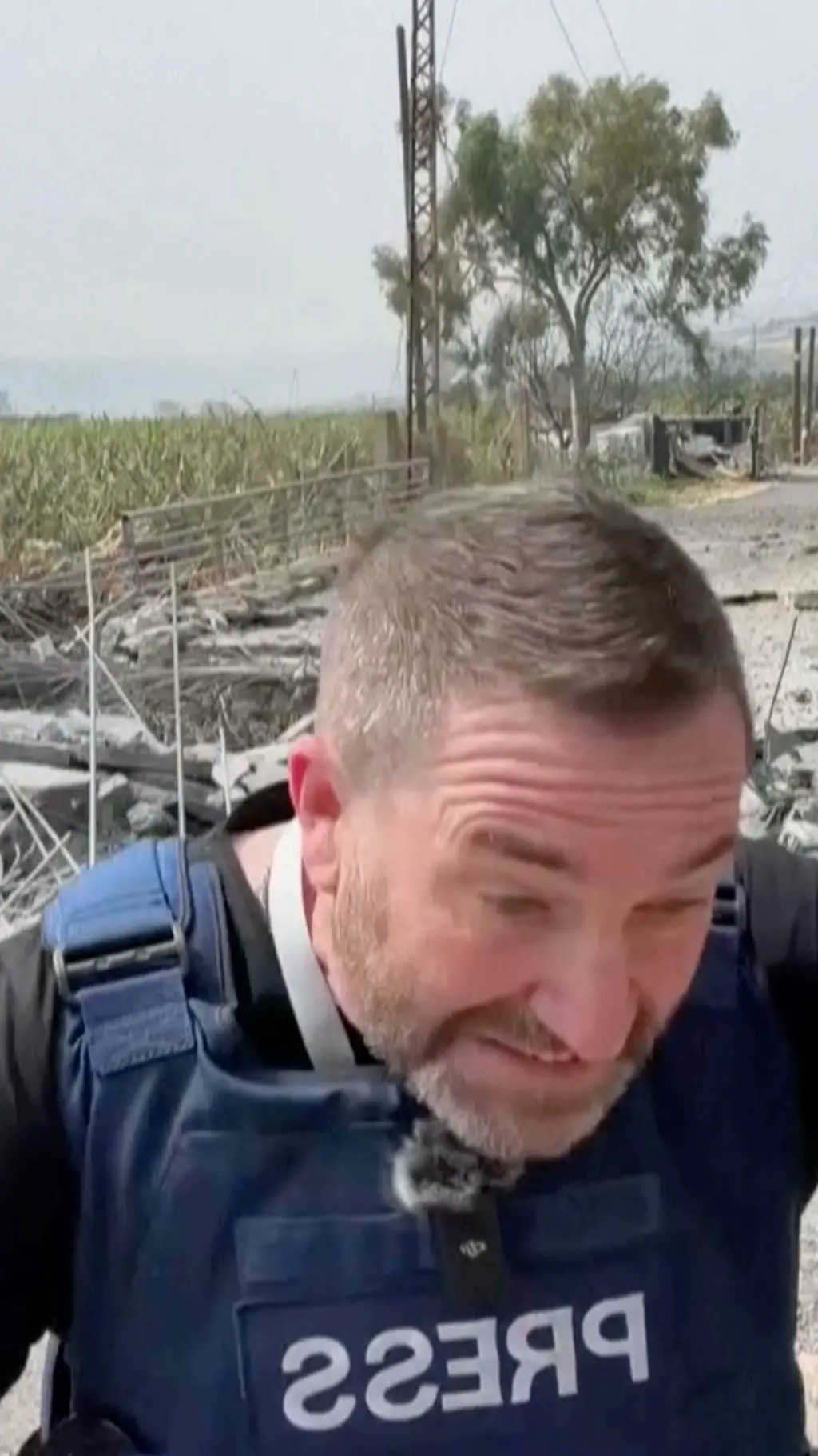 reporter u sigurnosnom prsluuku se saginje, iza njeg pada raketa