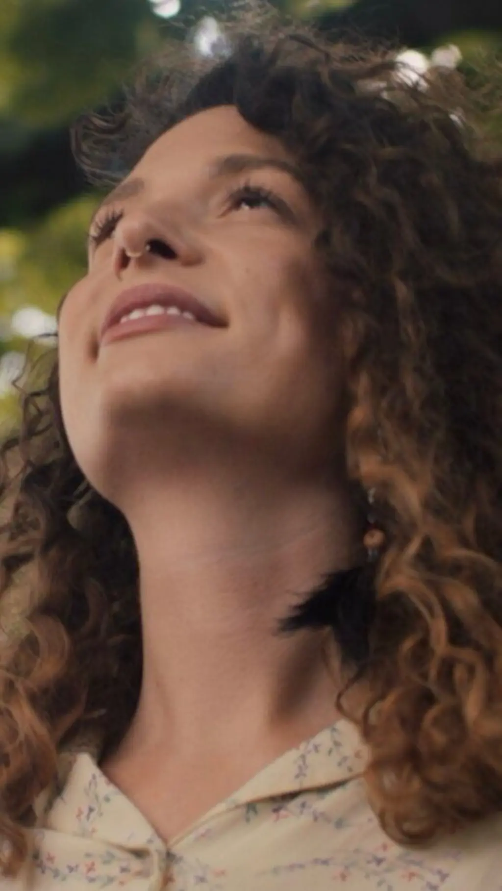 තරුණියක් සිනහමුසු මුහුණින් ගසක් දෙස බලා සිටි 