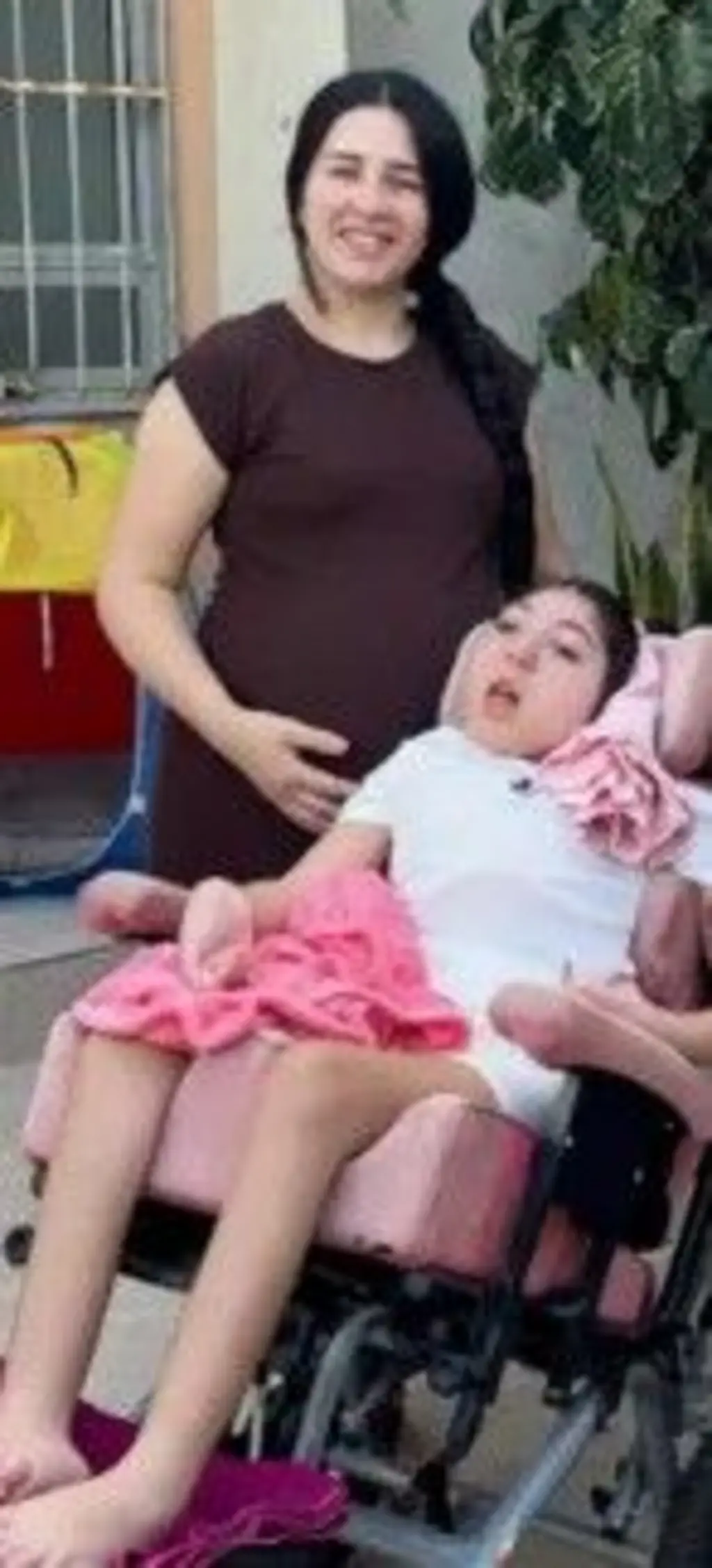 Mãe ao lado da filha que está em uma cadeira de rodas