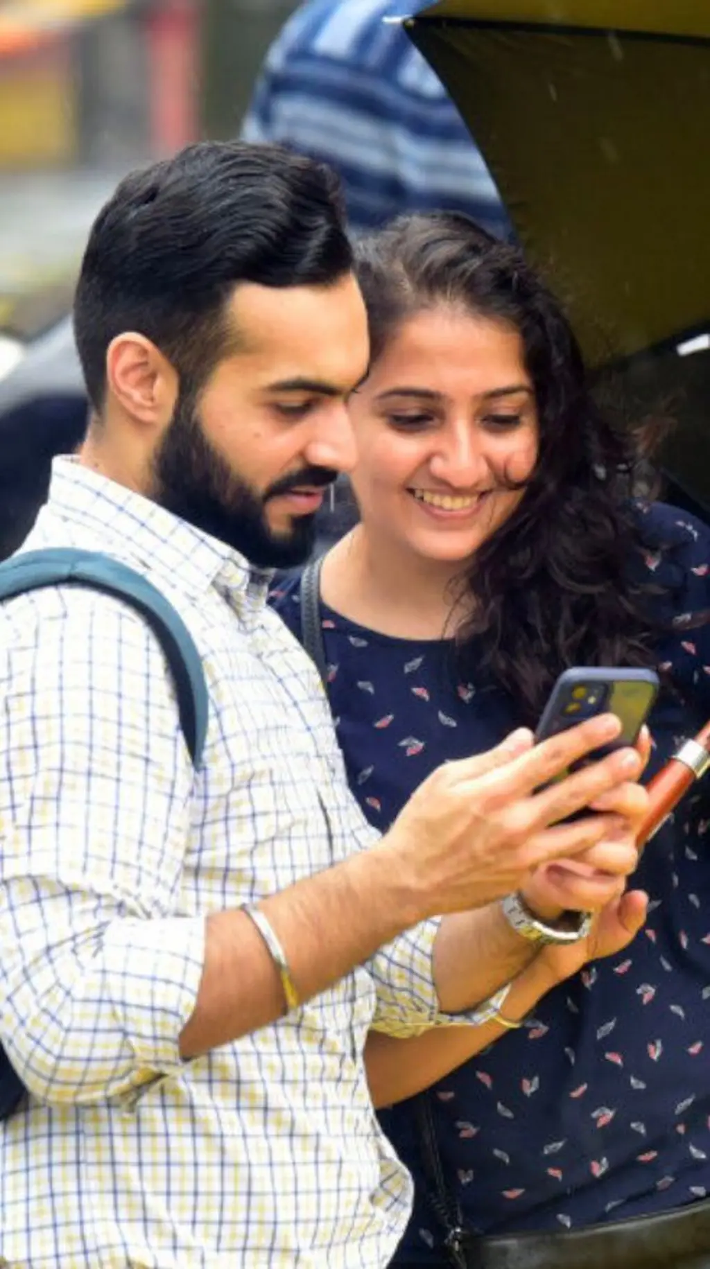 තරුණයෙකු සහ තරුණියක් සිනා සෙමින් ෆෝන් එකක් බලයි.