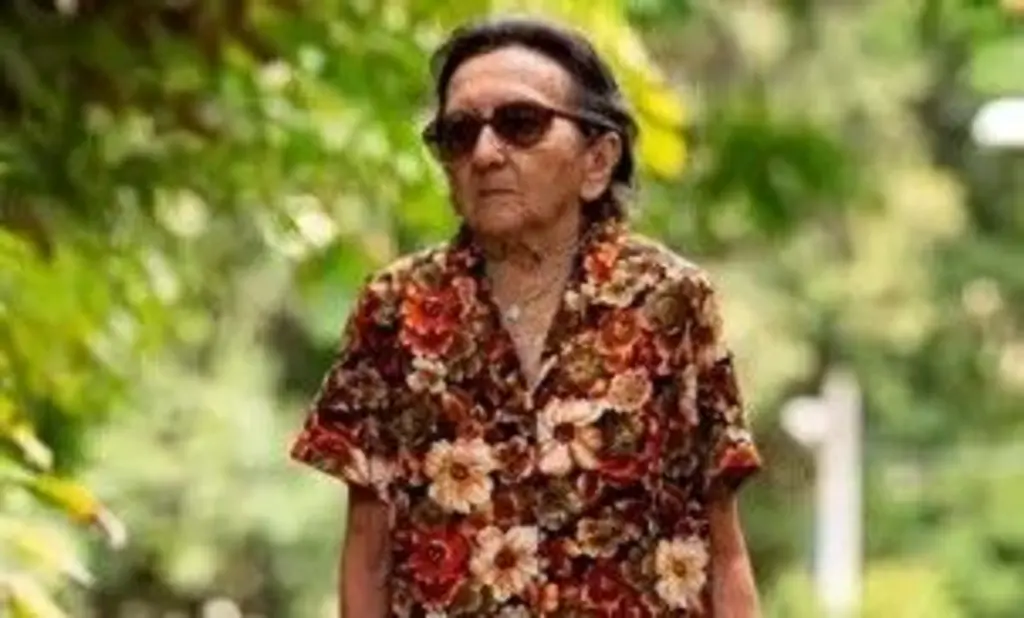 Tânia Maria em uma das cenas do filme. Ela usa um vestido florido e óculos escuros