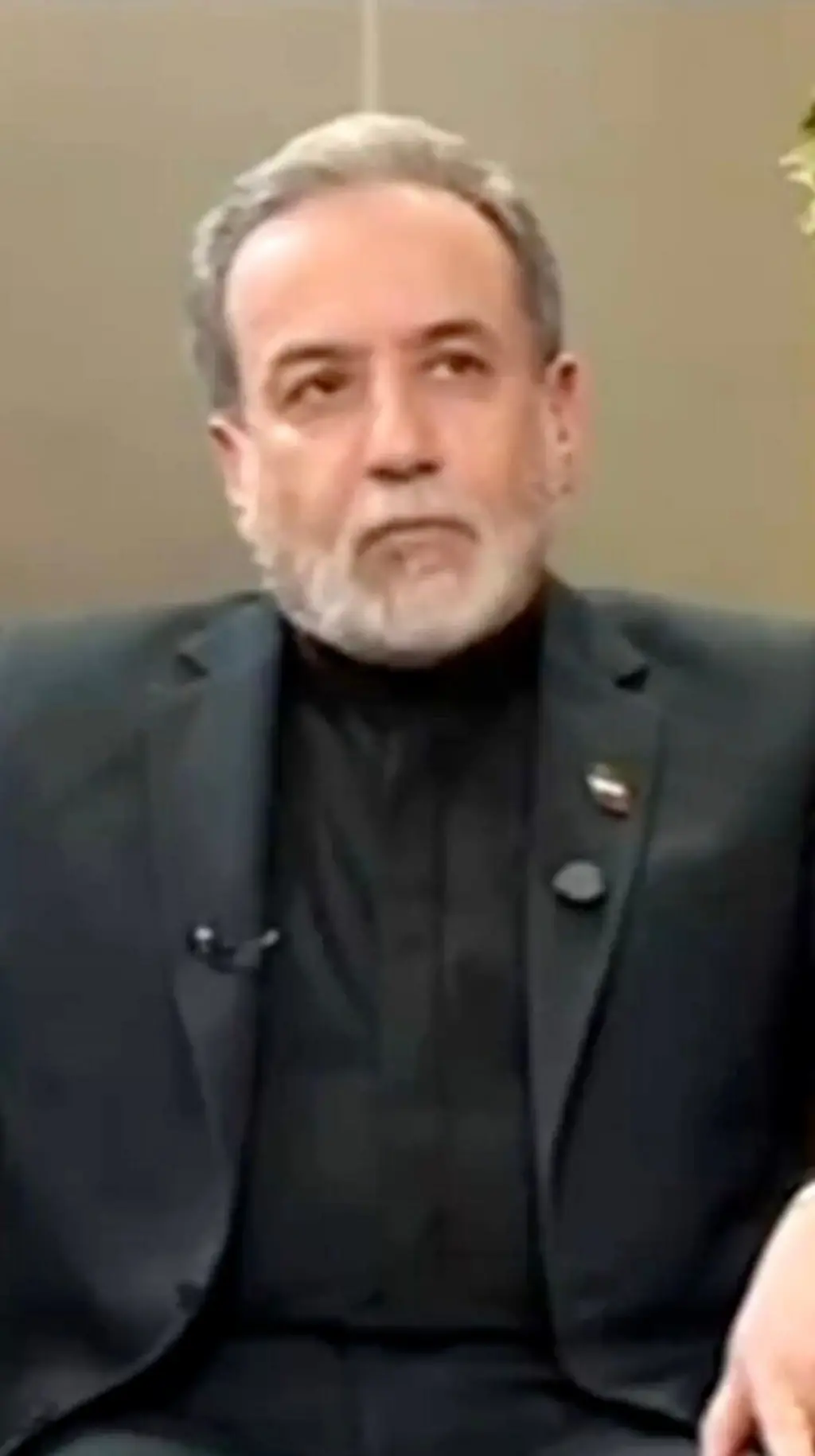 ඉරාන විදේශ අමාත්ය අබ්බාස් අරග්චිගේ ෆොටෝ එකක් මෙහි දැක්වෙන අතර ඔහු කළු පාට කොට එකකින් සැරසි සිටි.