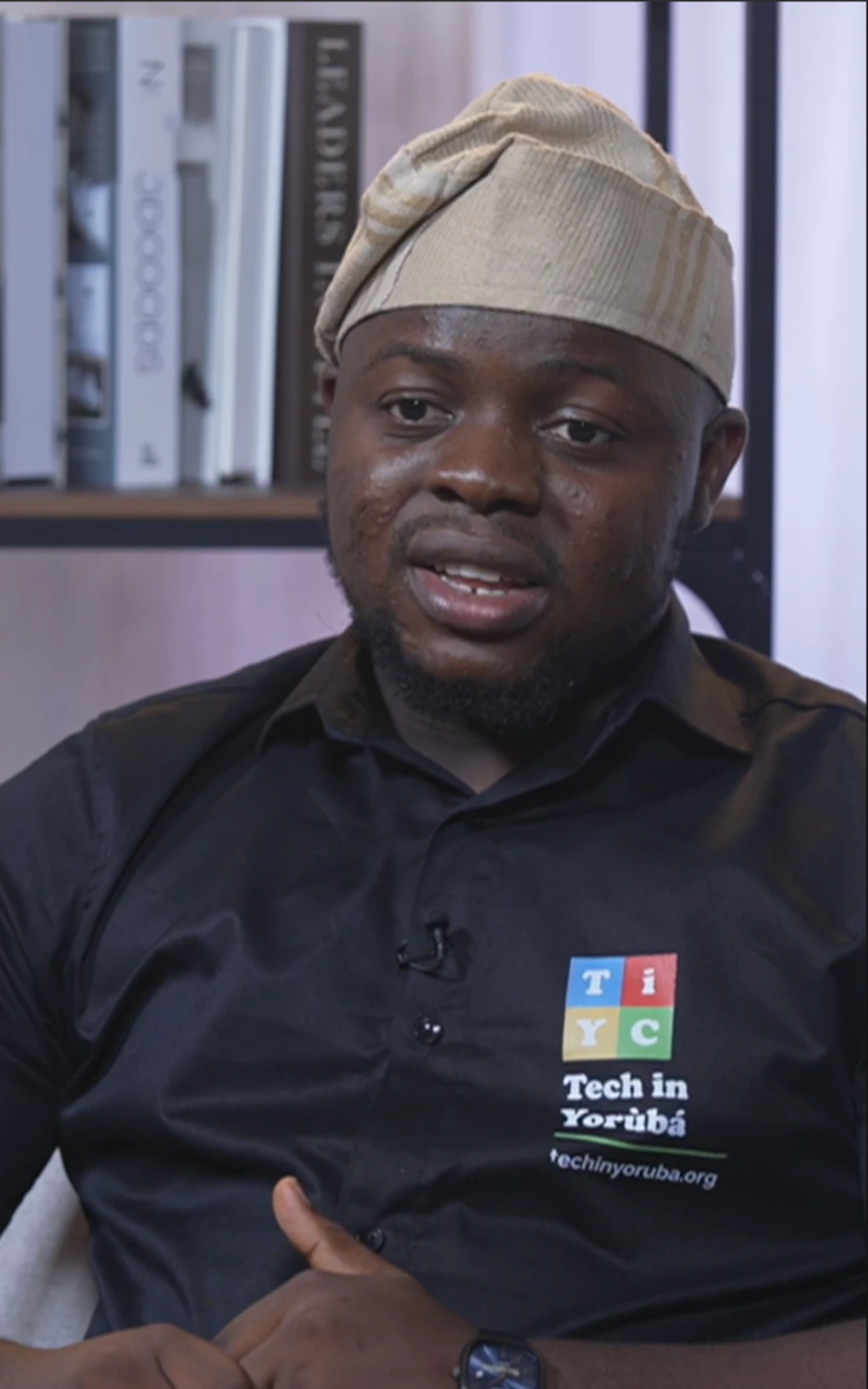 Theophilus Adegbohungbe to n fi ede Yoruba kọ awọn eeyan ni Tech wọ asọ sokoto ati ẹwu olomi aro ati fila alawọ goolu