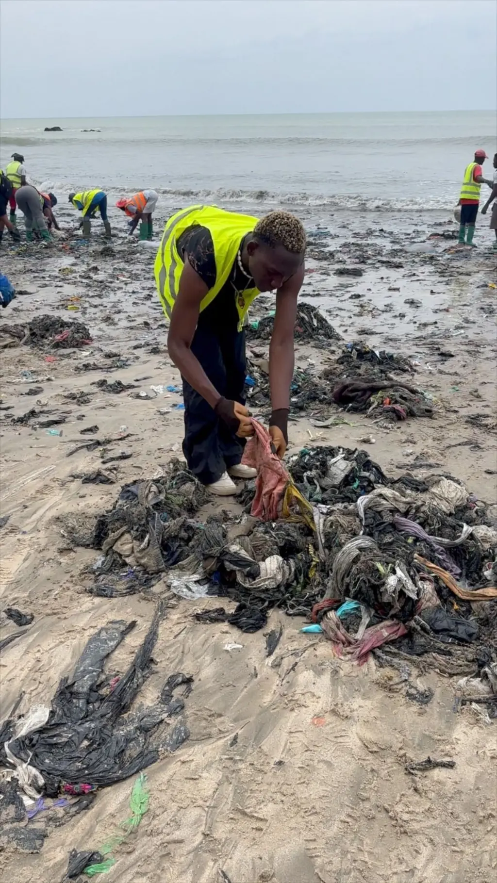 A man bends over rubbish of used clothes