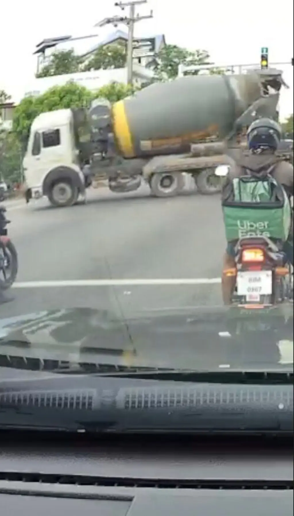 සිමෙන්ති මිශ්‍ර කරන ඉදිරිපස සුදු පාට ලොරියක් තාර පාරක ගමන් කරන ආකාරය පෙනේ.