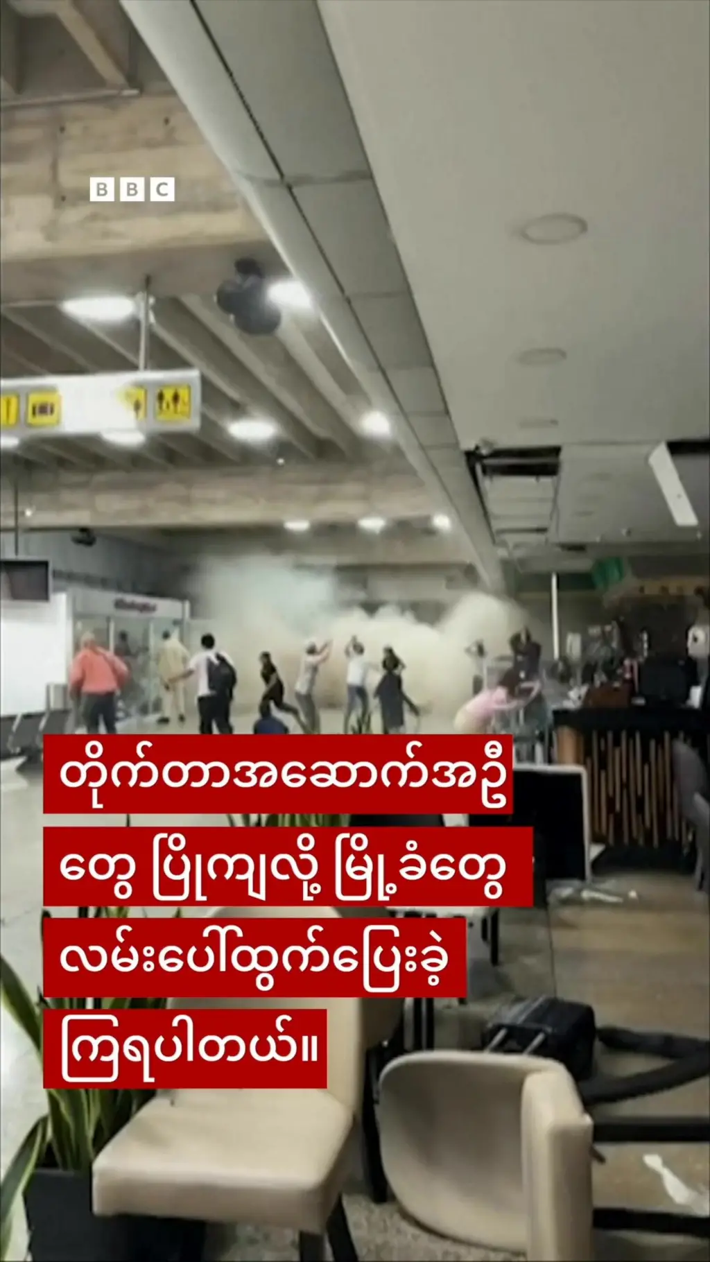 ကာရာကတ်စ်မြို့မှာ ဖြစ်ခဲ့တဲ့ ငလျင်ကြီးလှုပ်ခတ်မှုအတွင်း ''အဆောက်အဦပြိုကျလို့ မြို့ခံတွေ လမ်းပေါ် ပြေးထွက်ခဲ့ကြရပါတယ်'' ဆိုတဲ့ အဖြူရောင်စာနဲ့ အနီရောင်ဘား စာတန်းကို အနောက်မှာ အဆောက်အဦ တစ်ခုအောက် လူတစ်ချို့ အုတ်အုတ်ကြက်ကြက်ဖြစ်နေတဲ့ပုံ 