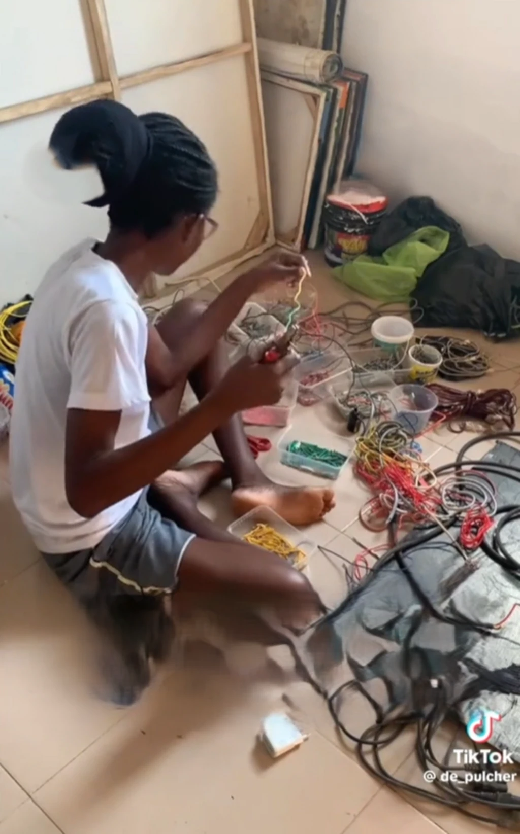 Patience Adekunle wọ sokoto penpe ati asọ T-Shirt, o tẹri mọlẹ n to waya to fẹ fi ya aworan