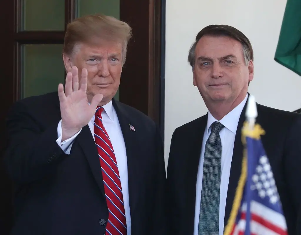 Donald Trump acenando para pessoas ao lado de Jair Bolsonaro