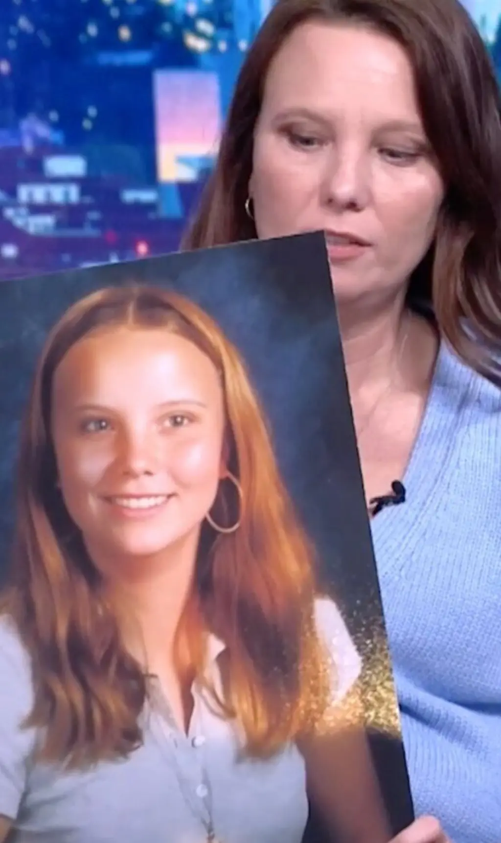 ලා නිල් පැහැති ගවුමකින් සැරසී සිටින මැදිවියේ කාන්තාවක් ඇගේ තරුණ කාලයේ ෆොටෝ එකක් අතේ තබාගෙන සිටී.