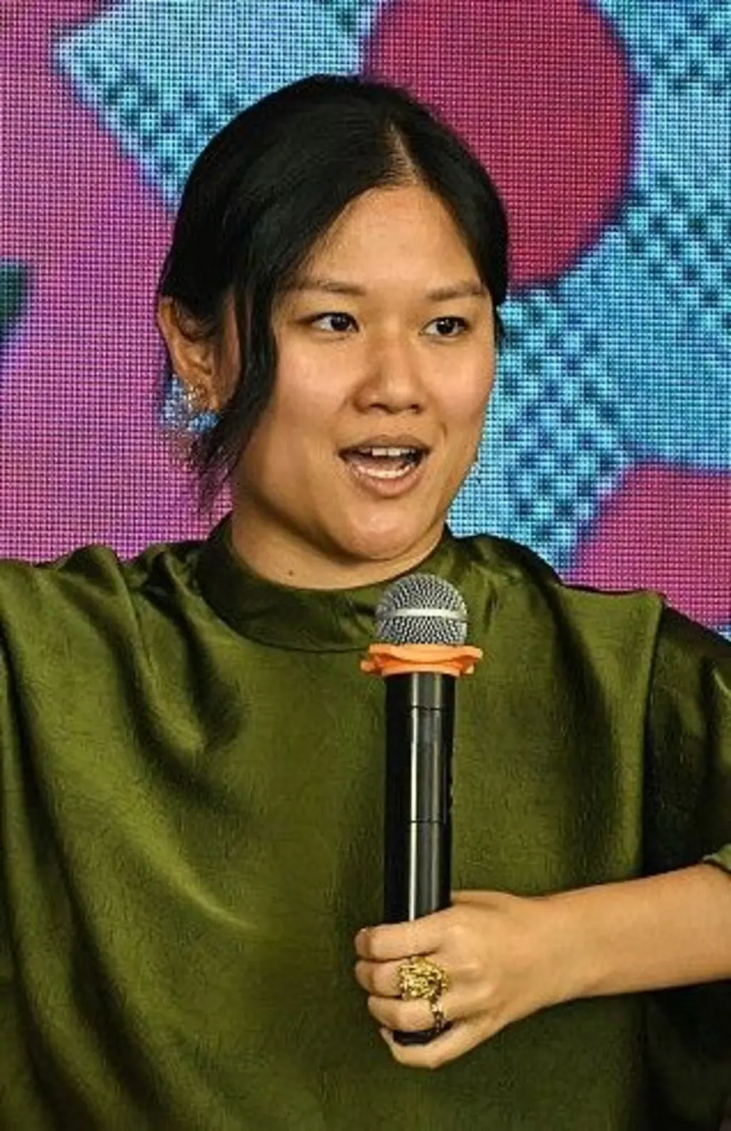 Karen Hao usando um vestido verde e segurando um microfone