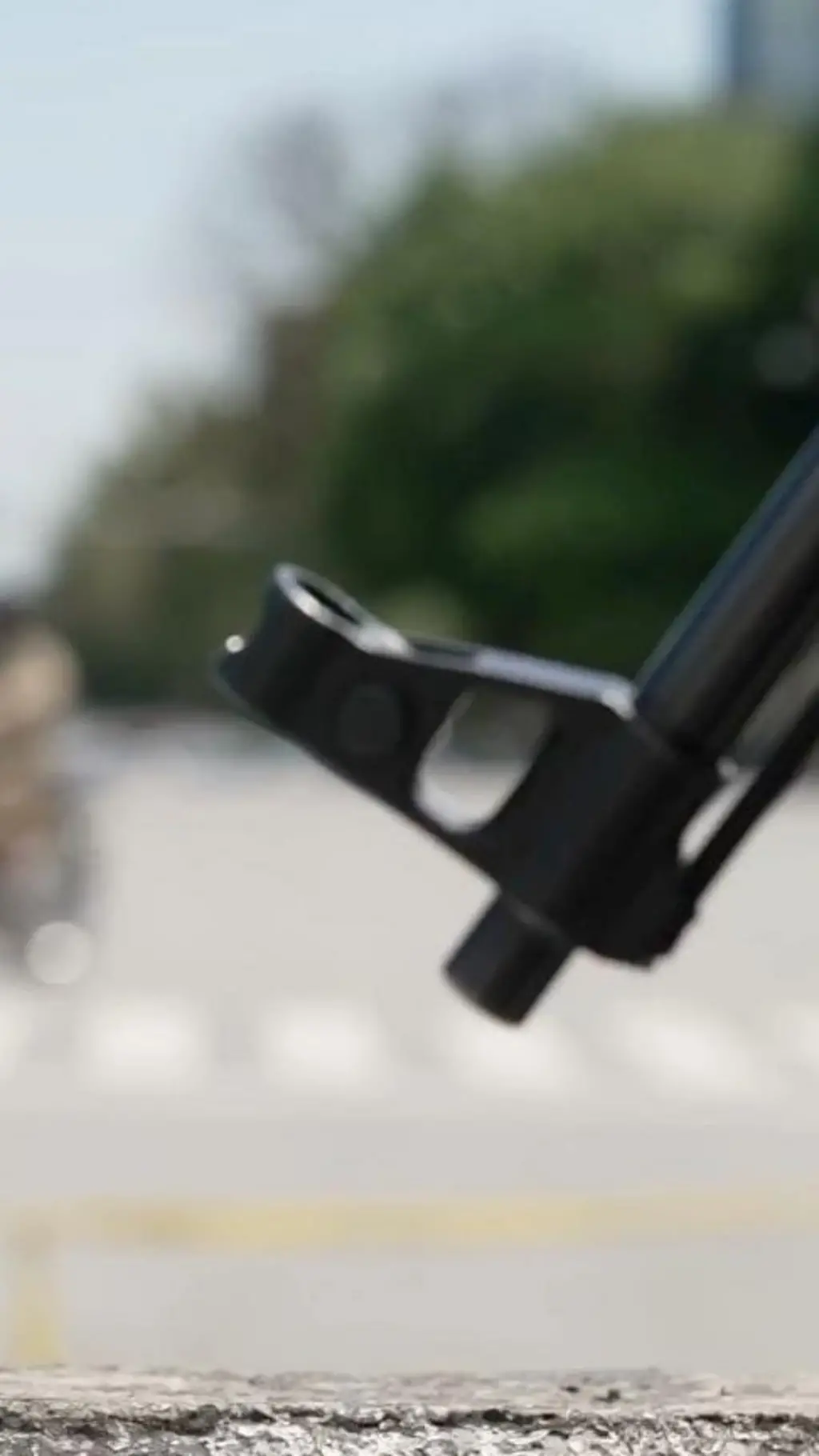 لوله تفنگ یک سرباز پاکستانی در حالیکه در پس زمینه یک موترسایکل از سرک عبور میکند