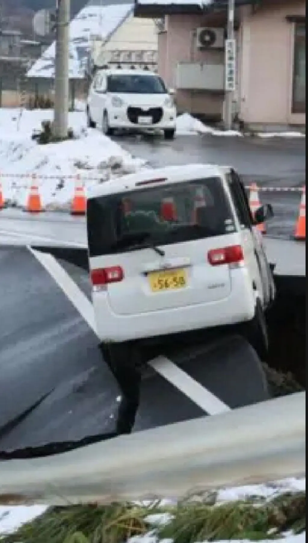 තාර පාරක් පුපුරා වැලක් සෑදී ඇති අතර සුදු පාට කුඩා වෑන් රථයක් එහි වලකට වැටි තිබේ.