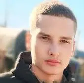 Retrato de Aleksandr Vinshu, um jovem de cabelos bem curtos vestindo uma blusa preta.