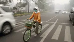 En invånare i Riau-regionen måste bära en mask mitt i rökdis.