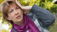 امرأة تمسك برأسها