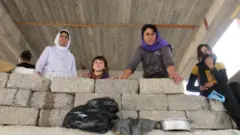 نساء من الإيزيديين يطللن من مبنى غير مكتمل
