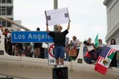 Un joven con un letrero parado encima de un semáforo en Los Ángeles