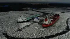 Два великі судна у порту, оточені кригою