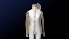 A white mannequin is dressed in a yellow-tinted transparent raincoat.