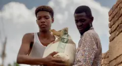 شابان يحاولان استخدام أكياس من الرمال للتصدي لمياه الفيضان