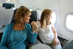 Annette e sua filha de mãos dadas sentadas em um avião e olhando a janela.