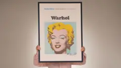 Una persona sujeta un cuadro de Warhol de Marilyn Monroe