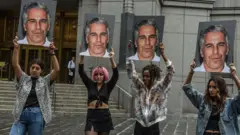 چند معترض عکس‌های جفری اپستین را در دست بالا گرفته‌اند