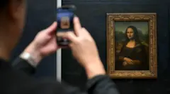 Una persona toma una foto de la Mona Lista con un móvil