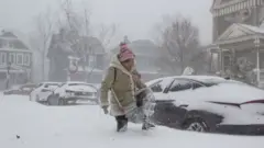 una mujer intenta caminar por la calle llena de nieve.