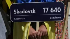 Українська активістка тримає табличку з написом "Скадовськ" під час саміту НАТО у Мадриді у червні