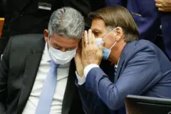 O então presidente , Jair Bolsonaro, fala com o presidente da Câmara, Arthur Lira, durante a sessão de abertura do Legislativo em Brasília, em 2 de fevereiro de 2022. Ambos usam máscaras de proteção contra a covid-19