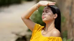 सूर्यकिरणांपासून बचाव करणारी तरुणी