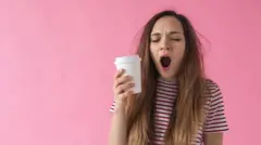 دختری لیوان بدست خمیازه می‌کشد