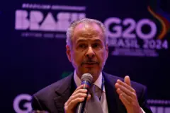 André Corrêa do Lago com microfone na mão em evento do G20 com banner atrás de si