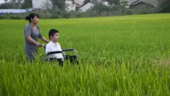 سيدة تدفع كرسي متحرك يجلس عليه رجل في حقل