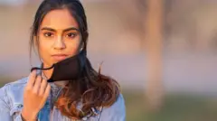 Portrait of an ethnic female standing outside wearing a protective face mask to avoid the transfer of germs during COVID-19