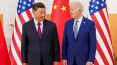 Xi Jinping e Joe Bidenaposta mais menospéaposta mais menosfrente a bandeiras, com sorrisos contidos