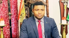 Simon Ekpa wear red tie wit suit, edey look straight.